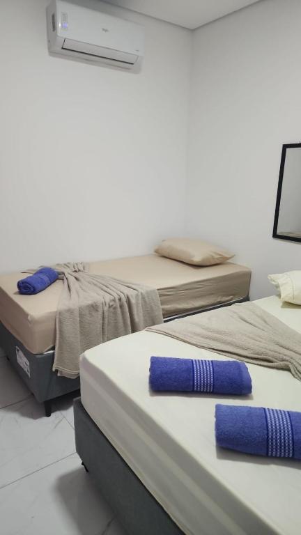 two beds in a room with blue pillows on them at kitnets Praia Super in Cumuruxatiba