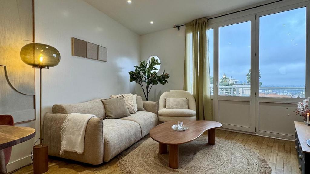een woonkamer met een bank en een tafel bij Vue Paris 1 min de la gare in Saint-Cloud