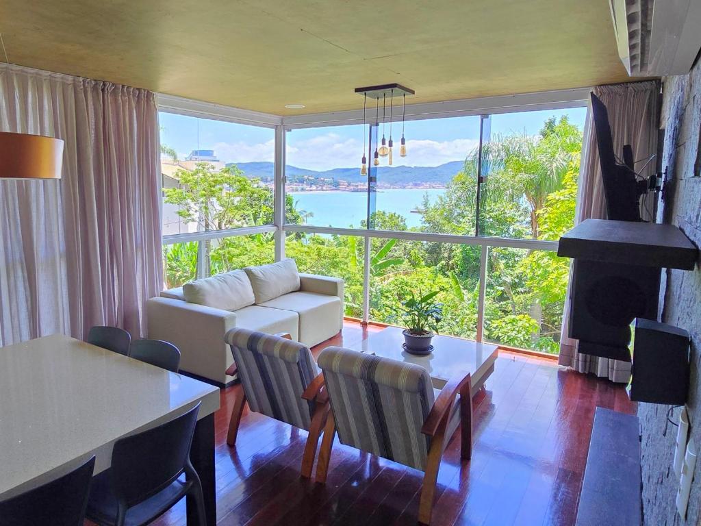 ein Wohnzimmer mit Tisch und großem Fenster in der Unterkunft Refúgio da Lagoinha - Centro de Bombinhas in Bombinhas