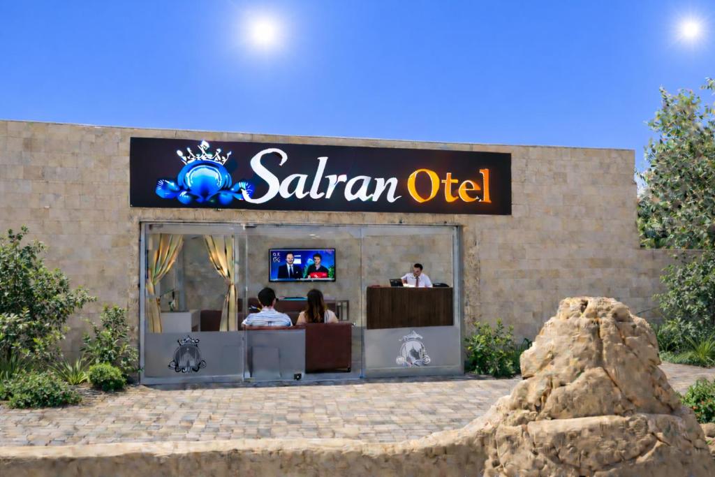 un cartello per un ufficio safari con persone sedute dentro di salran Otel a Sultan Koyu