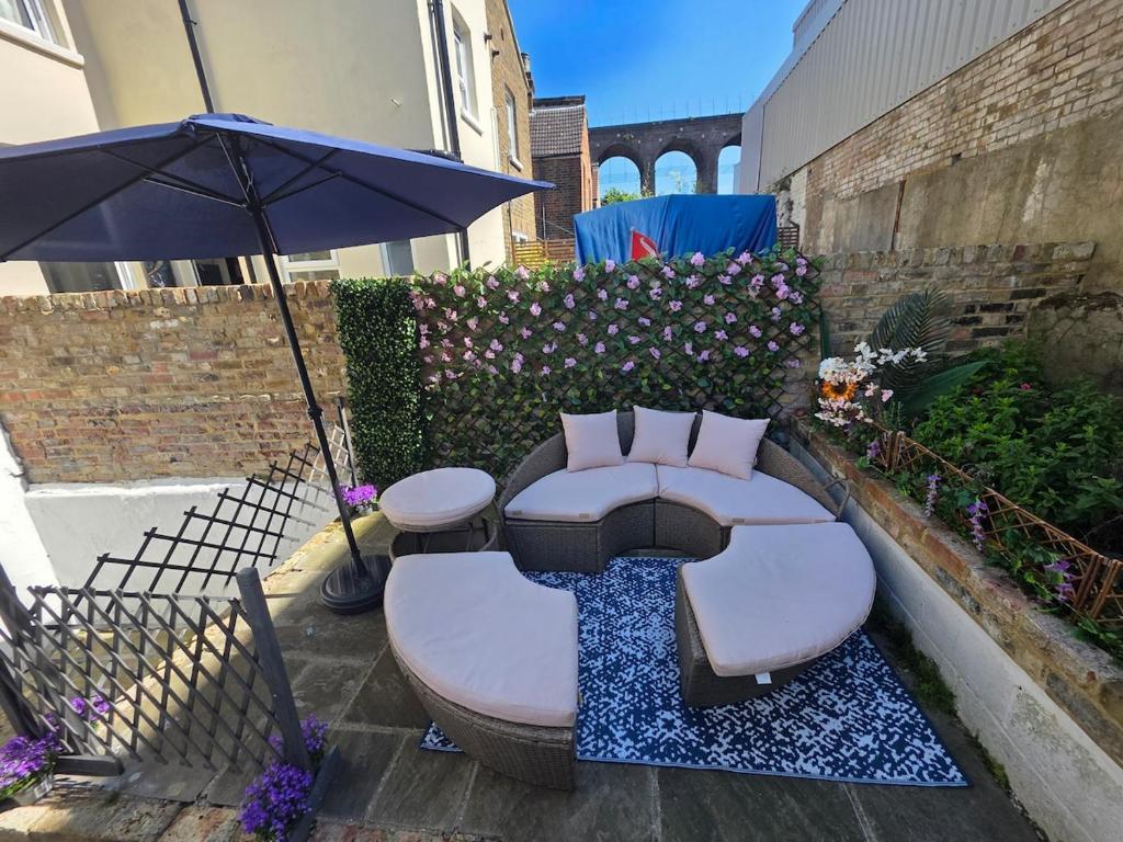 eine Terrasse mit einer Couch und einem Sonnenschirm in der Unterkunft Energy - 8ight Havens Folkestone in Folkestone