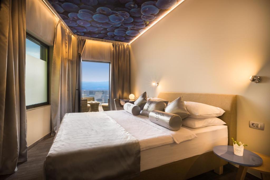a bedroom with a large bed with a large window at Hotel Vinotel Gospoja in Vrbnik