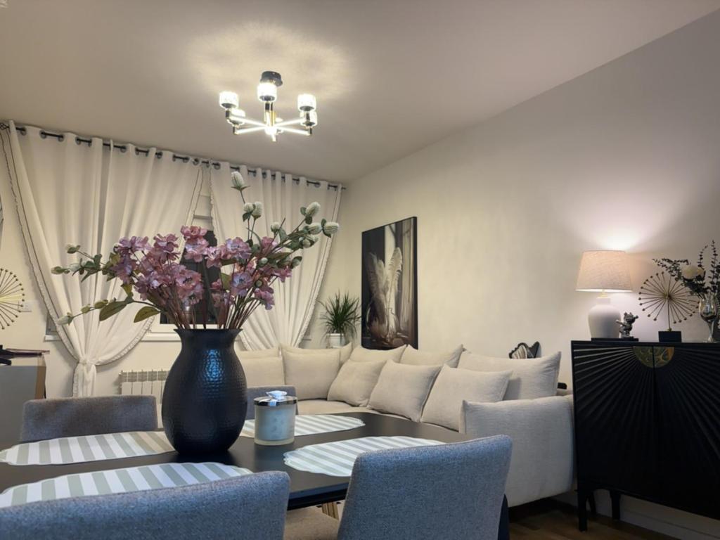 een woonkamer met een bank en een tafel met bloemen bij Stan na dan Bor Apartman in Bor