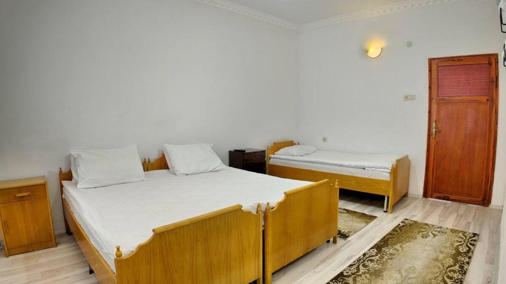 a bedroom with two beds and a wooden door at Gumus Hotel in Ortahisar