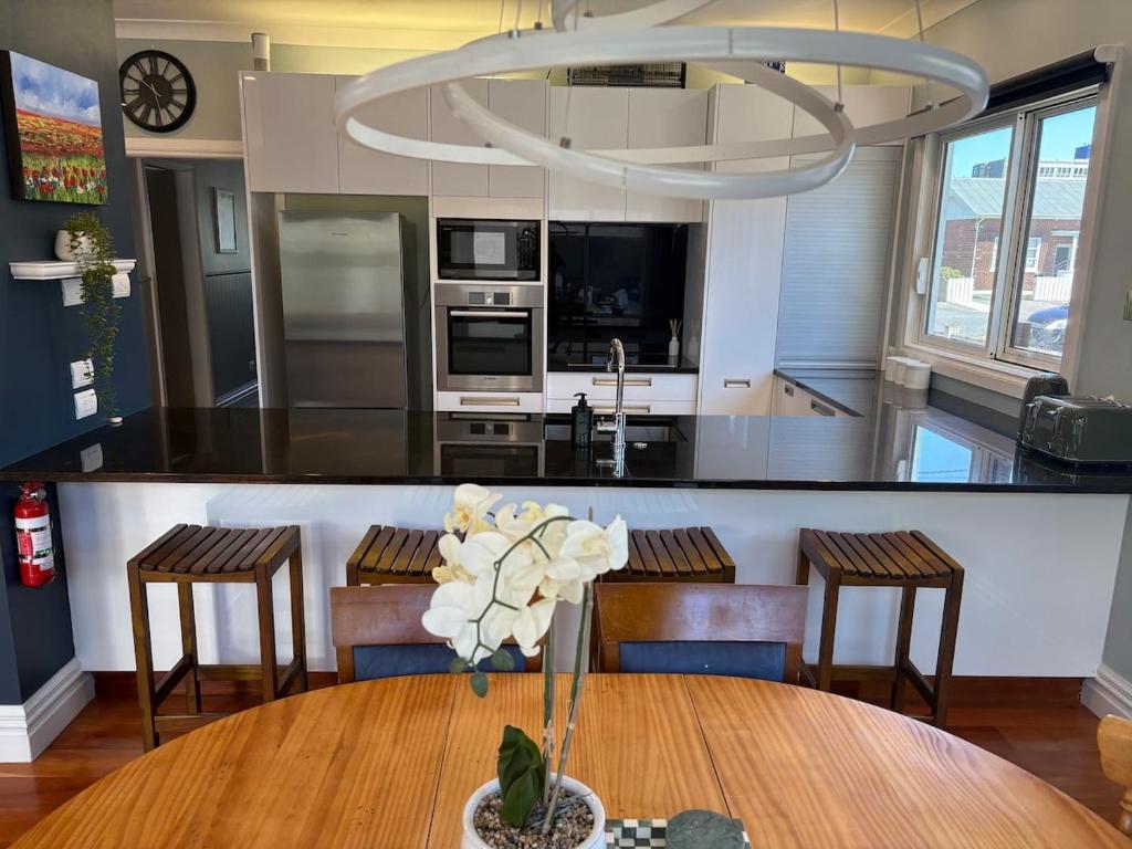 a kitchen with a table with a vase of flowers on it at Stylish Petone Stay in Lower Hutt