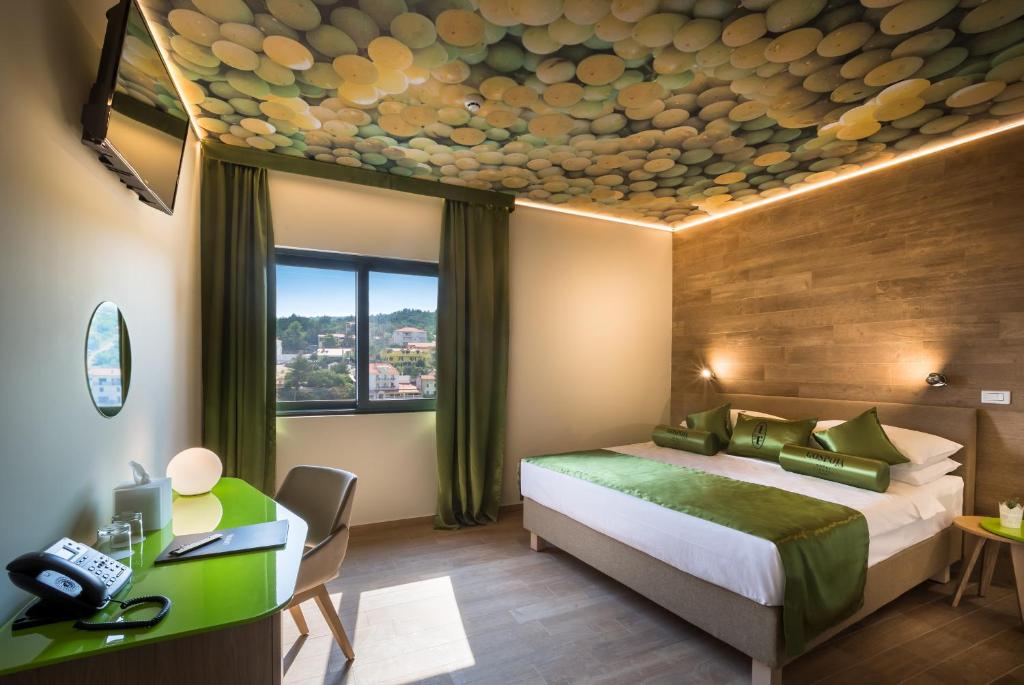 a hotel room with a bed and a desk and a window at Hotel Vinotel Gospoja in Vrbnik