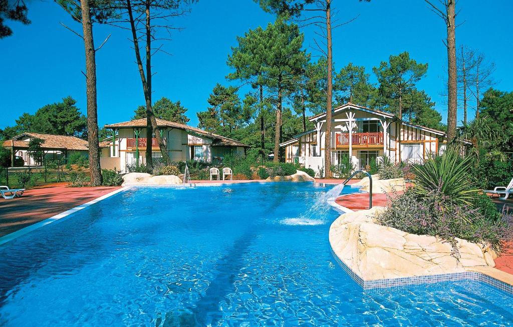 a swimming pool in front of a house at Résidence Odalys Les Greens du Bassin in Gujan-Mestras