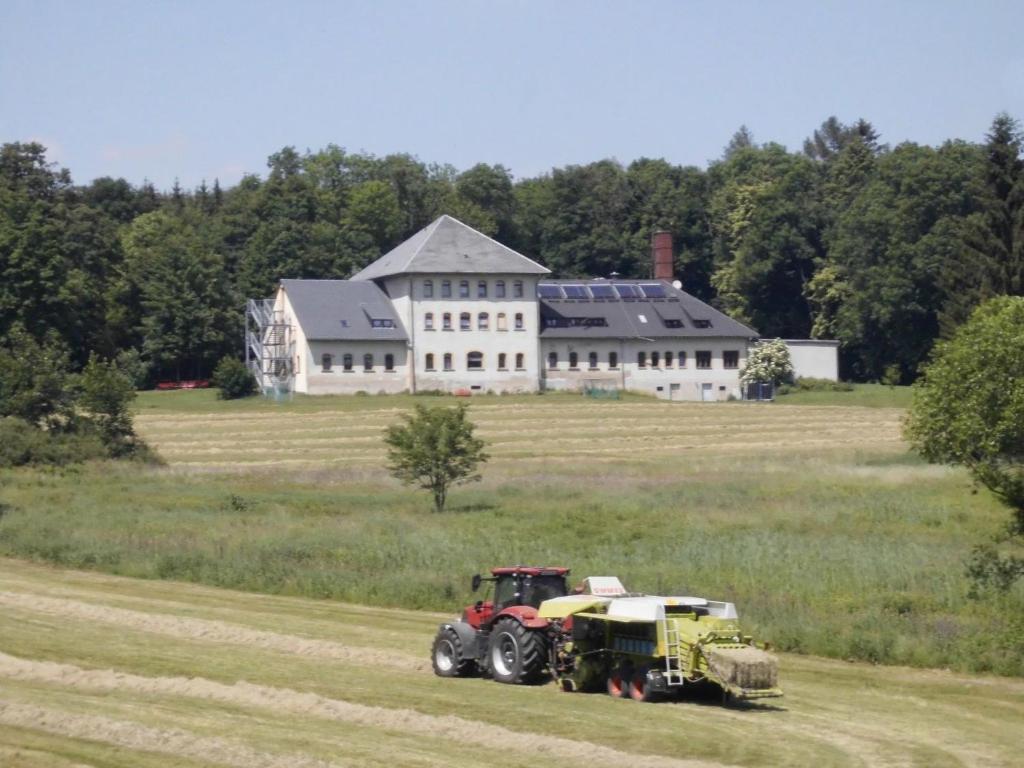 a tractor driving through a field in front of a large house at Apartment Saydaer Höhe by Interhome in Sayda