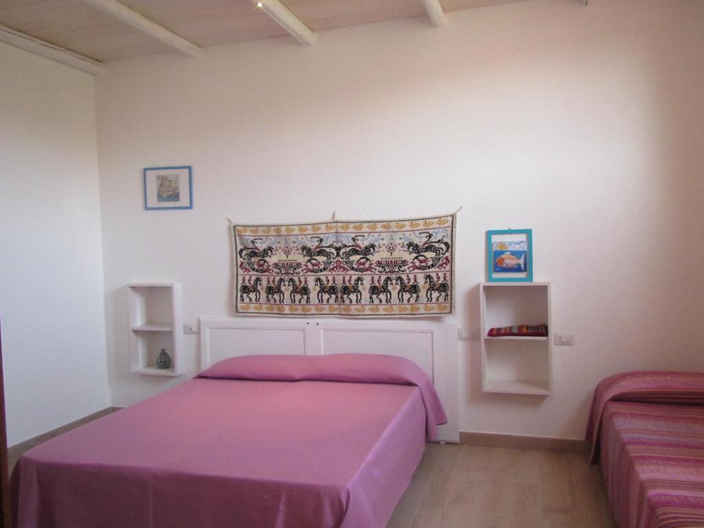 - une chambre avec un lit et une couverture violette dans l'établissement B&B Su Tostainu, à Teulada