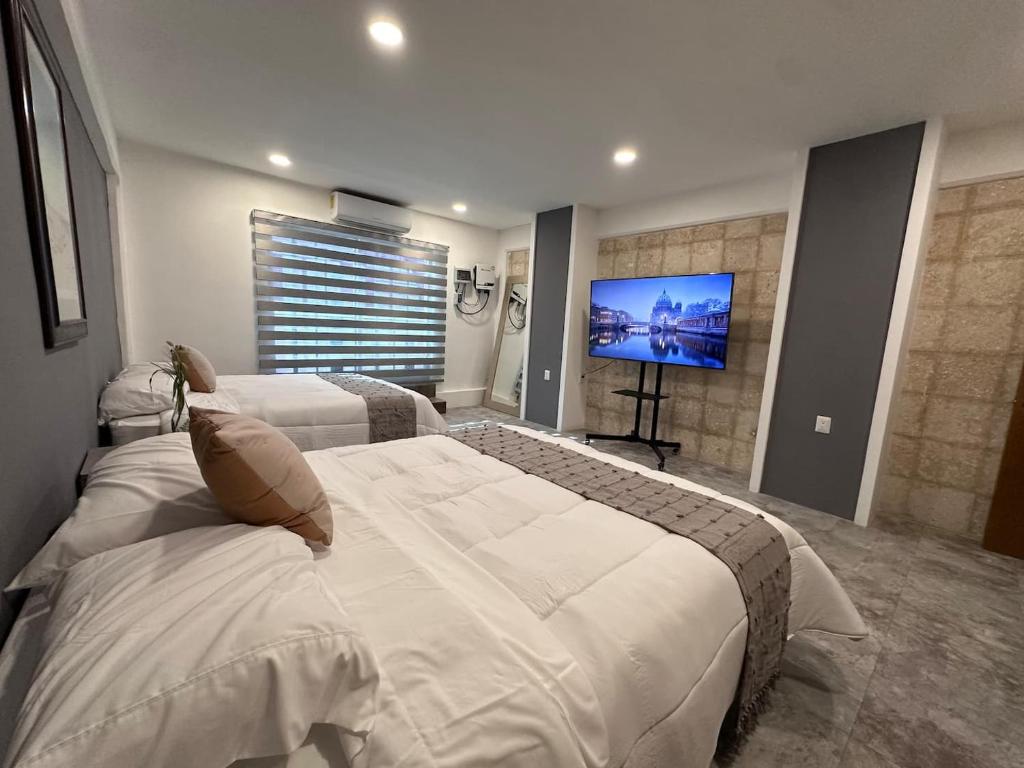 a bedroom with two beds and a flat screen tv at Steps from the Historic Center & Malecón in Campeche