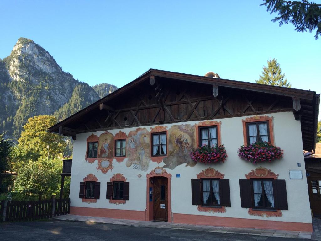 un edificio blanco con ventanas y flores negras en Ferienwohnungen im Lüftlmalereck, Mussldomahaus en Oberammergau