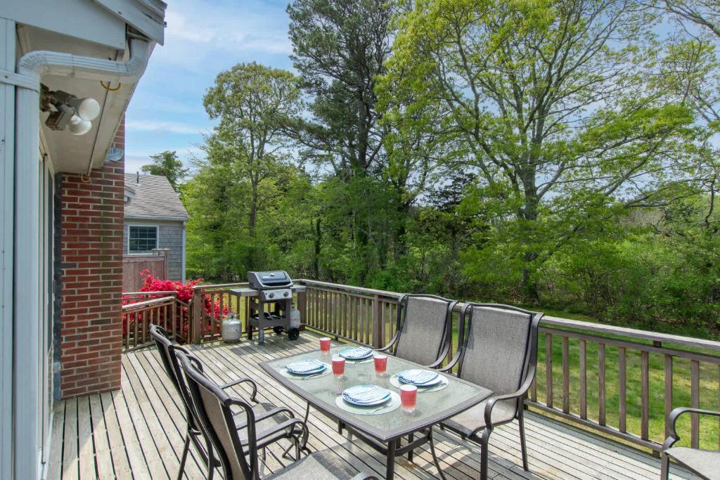 een tafel en stoelen op een terras met een grill bij The Perfect Beach Getaway in Orleans