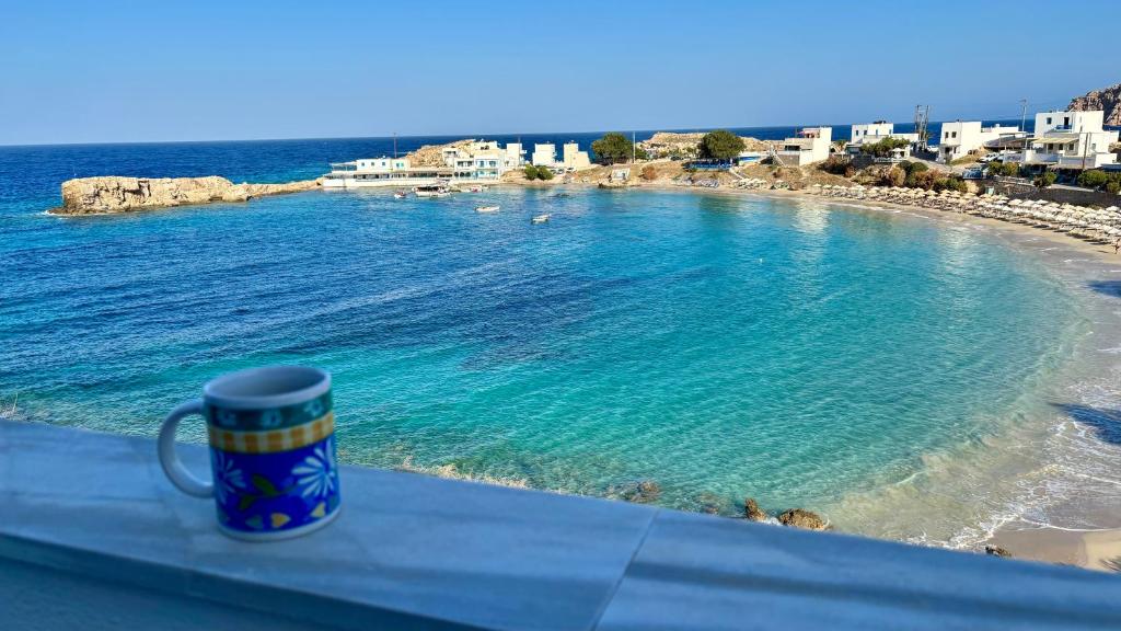 una tazza di caffè appoggiata su una sporgenza vicino a una spiaggia di Dina's Beach House a Karpathos