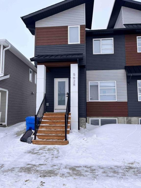 a house with stairs in the snow in front of it at Havilah's Place Regina in Regina