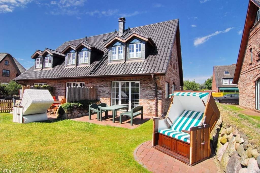 a house with a table and chairs in the yard at Gartenweg 3d in Tinnum
