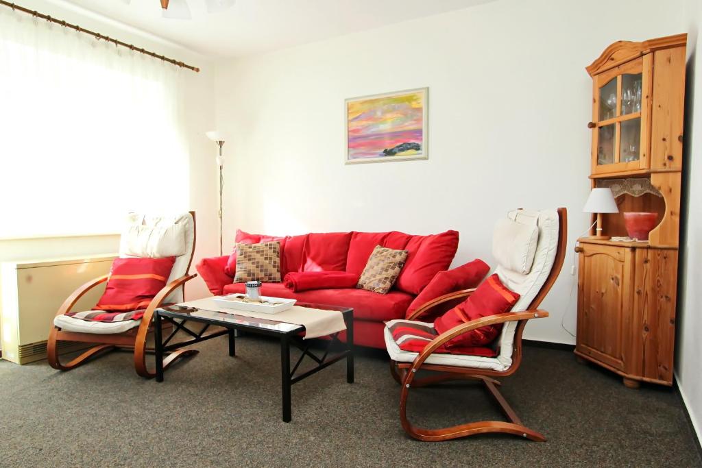 ein Wohnzimmer mit einem roten Sofa und Stühlen in der Unterkunft Silbermöwe in Hörnum