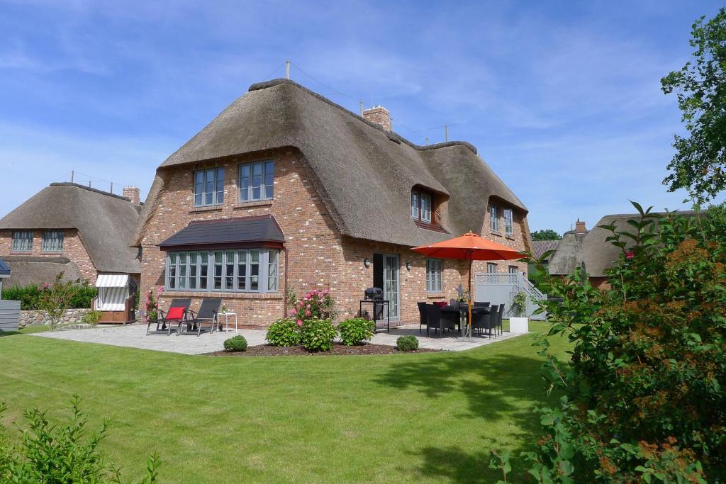 a large house with a thatched roof with a lawn at Simons Hüs in Oldsum