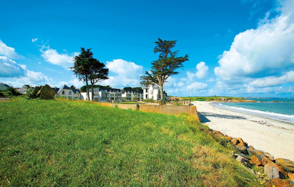 een strand met een huis en bomen en de oceaan bij Résidence Odalys Domaine des Roches Jaunes in Plougasnou