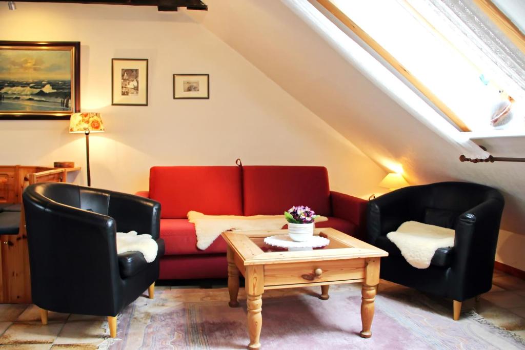 a living room with two chairs and a red couch at Lachmöwe in Hörnum