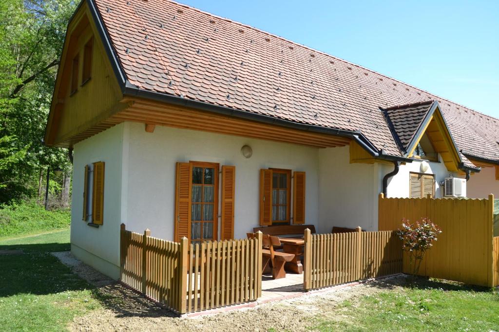 a small white house with a wooden fence at Apartma Marjetica 47 in Moravske Toplice