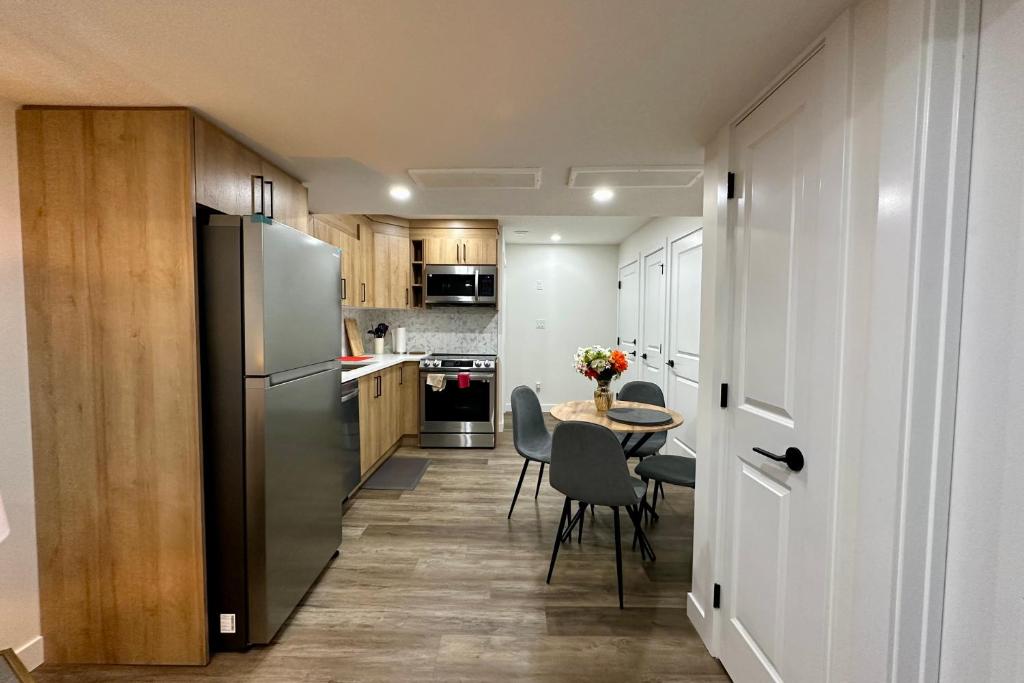 a kitchen with a table and a stainless steel refrigerator at Sleek Guest Retreat SW EDM BSMT Suite in Edmonton