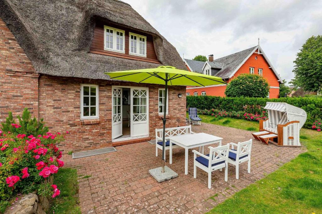 a patio with a table and chairs and an umbrella at Wynkaat in Nieblum