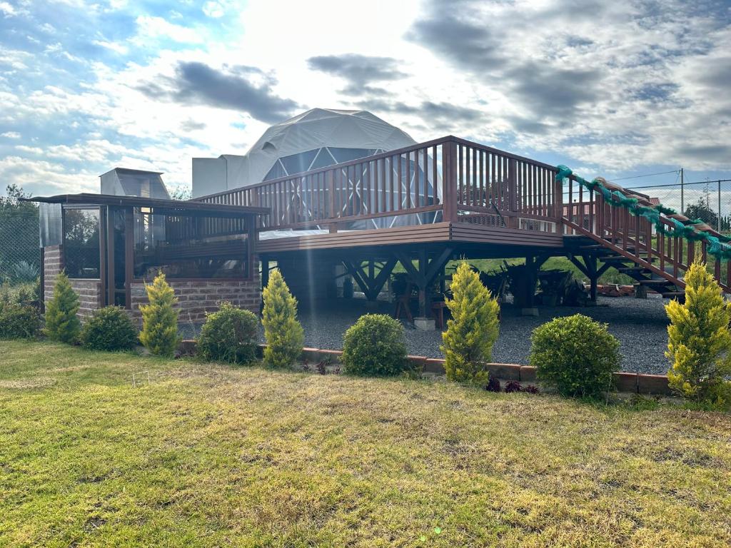 a house with a wooden deck and a playground at La cabaña de Ciela G glamping con jacuzzi y croquet in Latacunga