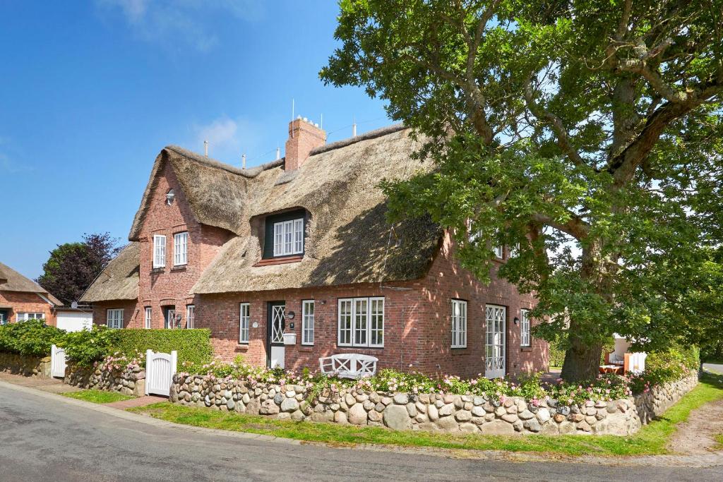 een oud stenen huis met een stenen muur bij Alte Eiche in Utersum