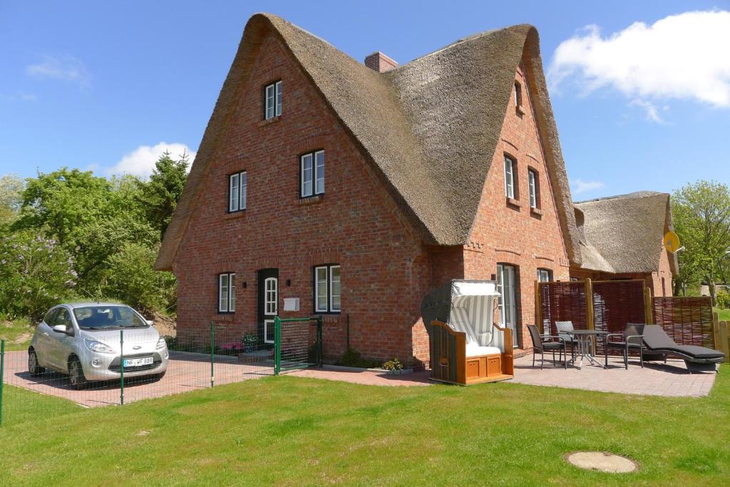 een groot bakstenen huis met een auto ervoor geparkeerd bij Strandnest in Witsum