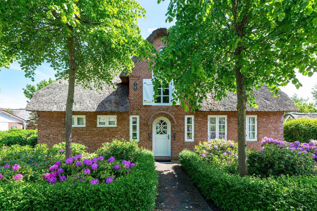 a brick house with flowers in front of it at Friesen-Kate-Oldsum in Oldsum