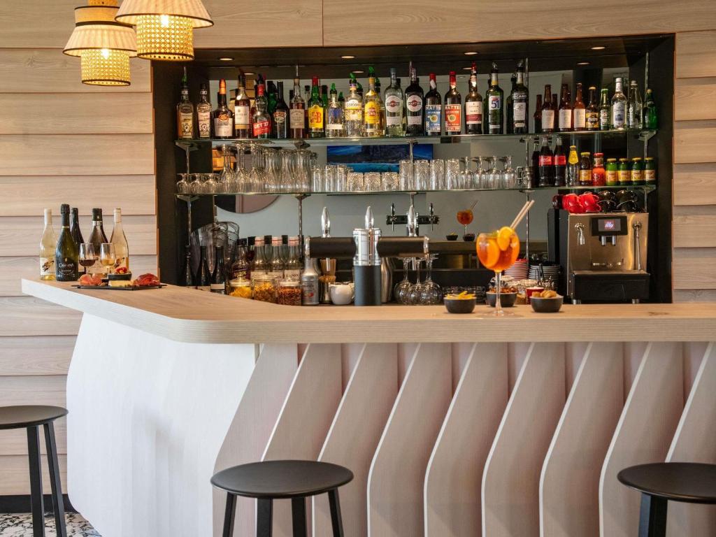 een bar met krukken en flessen alcohol bij ibis Styles Porto Vecchio in Porto-Vecchio