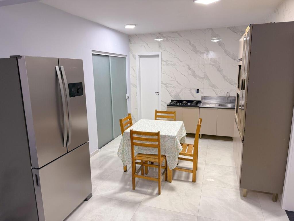 a kitchen with a table and chairs and a refrigerator at Recanto perto do mar com Jacuzzi in Camboriú