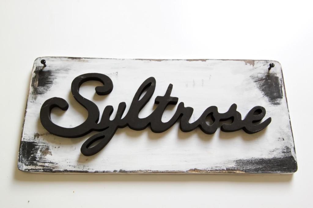 ein Schild mit dem Wort Lächeln an einer Wand in der Unterkunft Syltrose in Hörnum