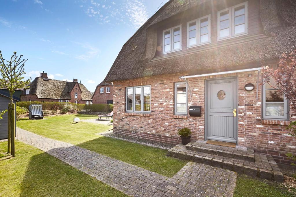a brick house with a blue door in a yard at Hüs Freesenborg in Oldsum