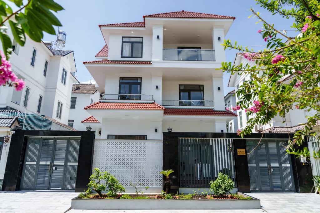a white building with black gates and pink flowers at HomyPlus Apartment in Ho Chi Minh City