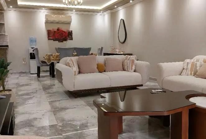 een woonkamer met twee witte banken en een tafel bij elwadaayan waady in Riyad