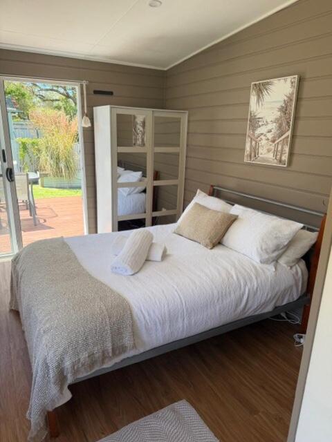a bedroom with a large bed with white sheets and pillows at Frangipani Studio PET FRIENDLY!!! in Ulladulla