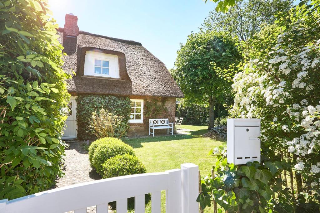 een klein huis met een wit hek in de tuin bij Haus Augenblick in Utersum