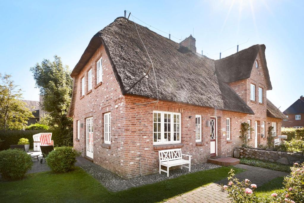 an old brick house with a thatched roof at Landhaus Meta in Wrixum