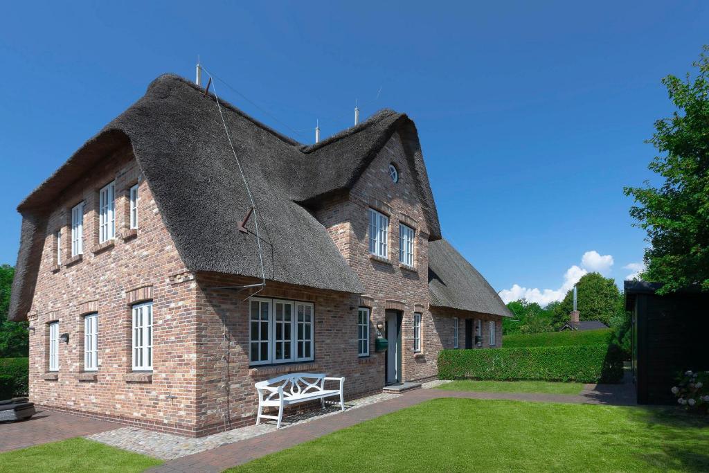 a brick building with a roof with a bench in the yard at Alt Wrixum Haus 1 in Wrixum