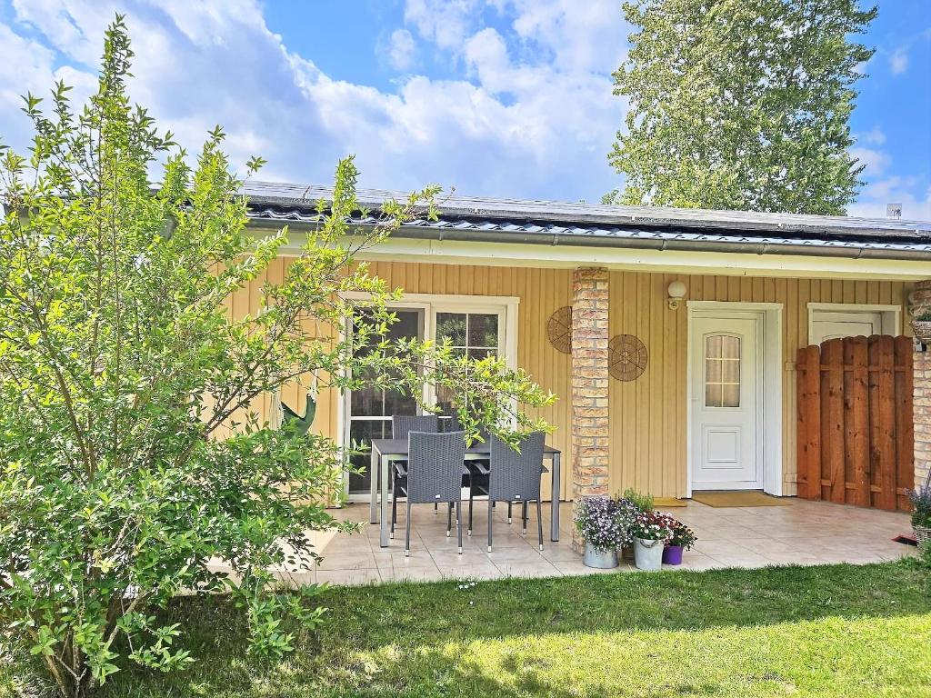 a small yellow house with a table and chairs at Ferienhaus Sommerwiese - ABC327 in Klein Warin