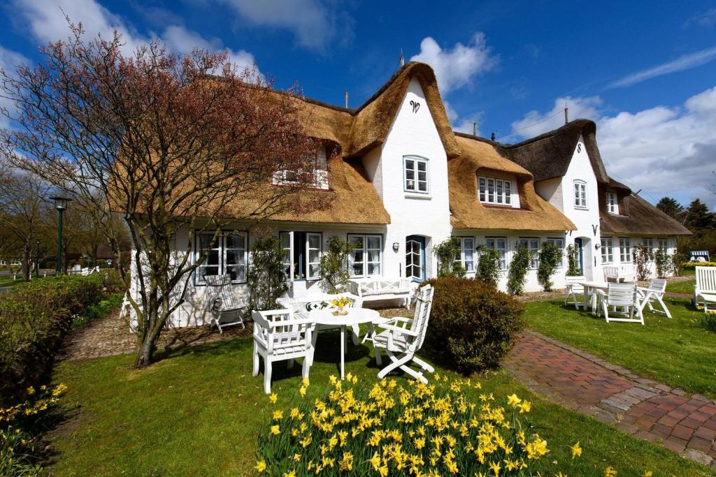 a house with a table and chairs in the yard at Entennest im Witthüs in Nieblum