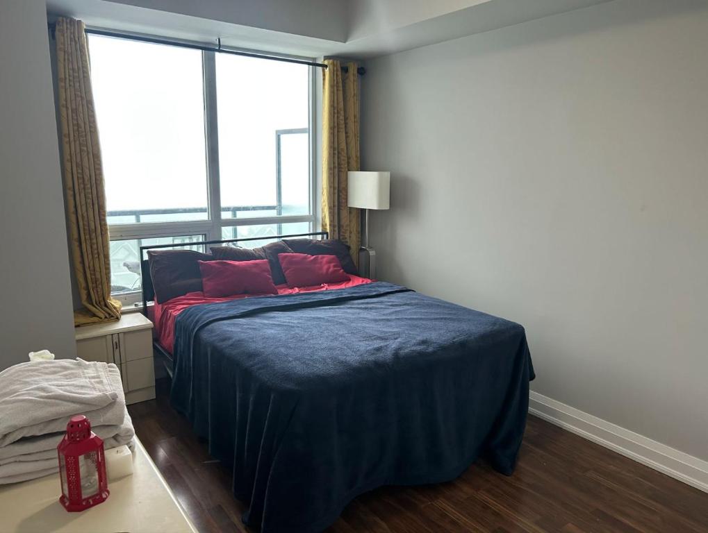 een slaapkamer met een bed met rode kussens en een raam bij Entire Place With Pool Sauna in Vaughan