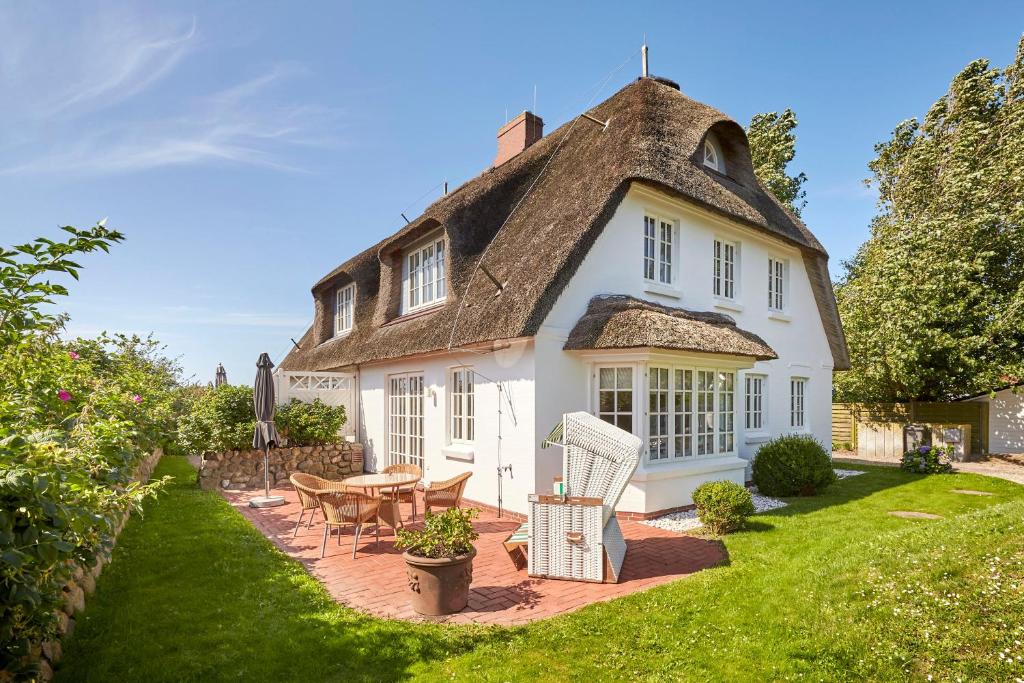 a house with a thatched roof with a table and chairs at Deichgraf in Dunsum