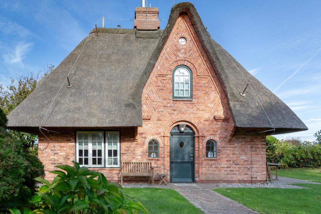 a small brick house with a thatched roof at Ferienhaus Hideaway in Kampen