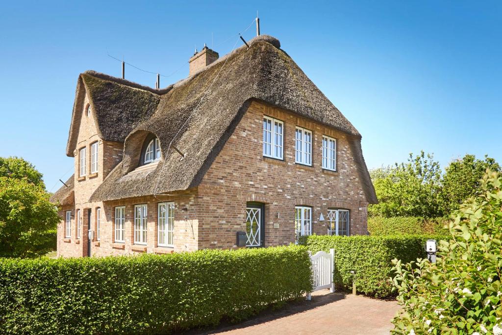 an old brick house with a thatched roof at Reethaus Friesenjung in Hedehusum