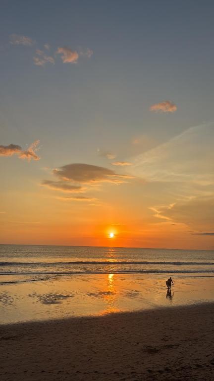 een persoon die bij zonsondergang op het strand loopt bij kedungu in Tanah Lot
