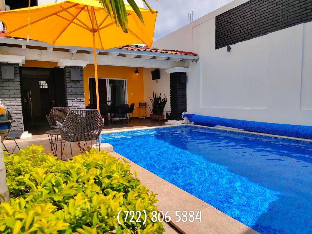 una piscina con un ombrellone accanto a una casa di Casa Rinconcito Del Sol Alberca Climatizada a Tonatico