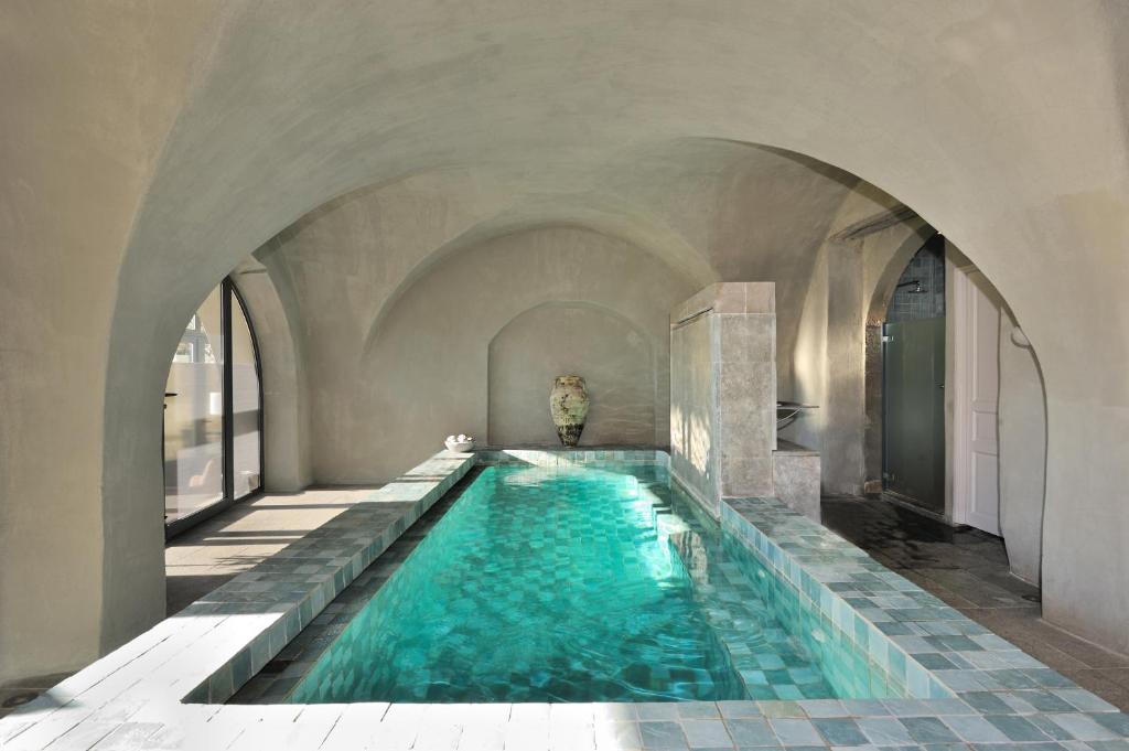 a swimming pool in a building with an archway at Le Couvent D'Herepian in Hérépian