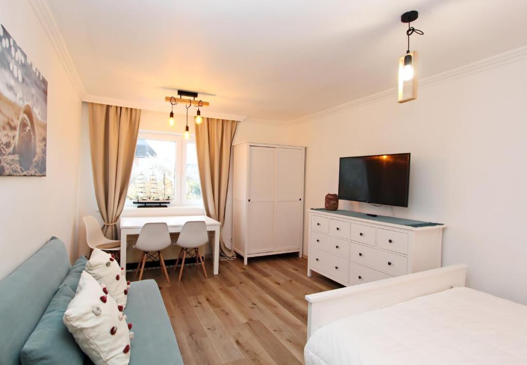 a bedroom with a bed and a desk with a television at Meer-Liebe in Hörnum